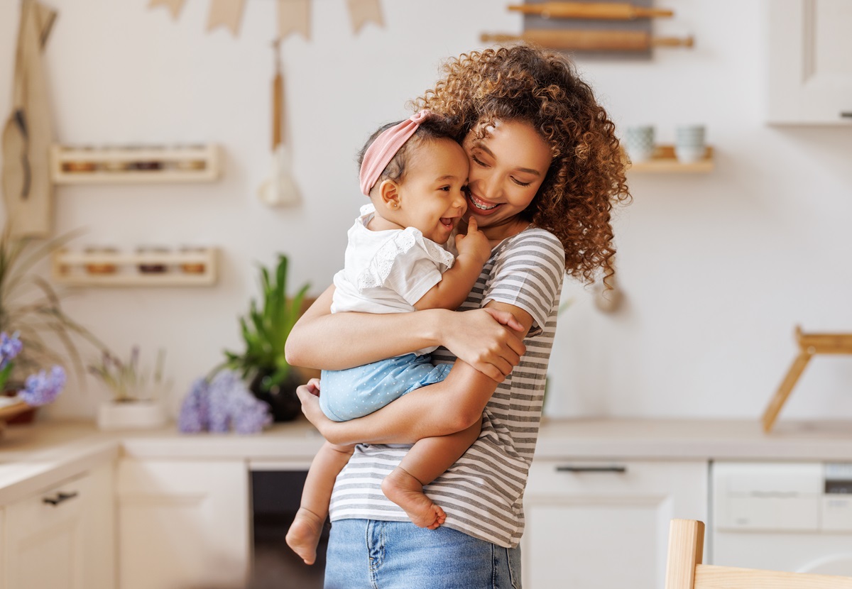 Mulher sorrindo carregando bebê; aplicativos para mães de primeira viagem