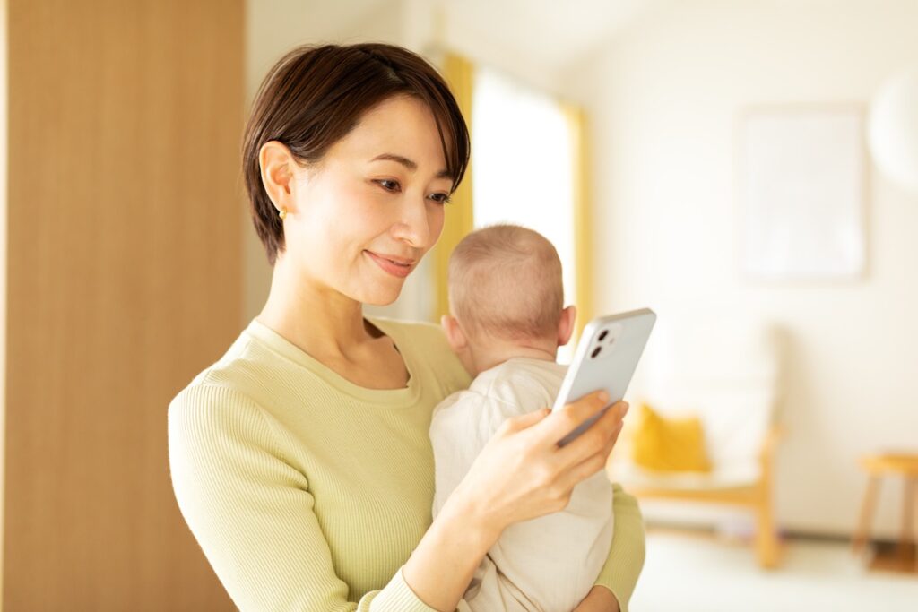 Mom using phone while holding her baby