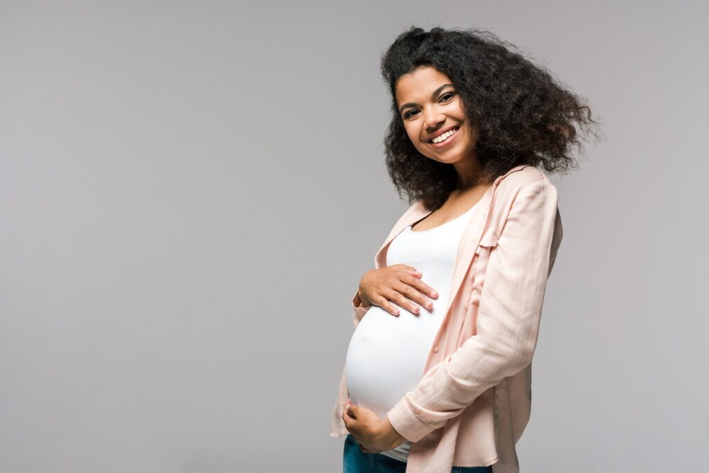 cheerful pregnant woman touching belly