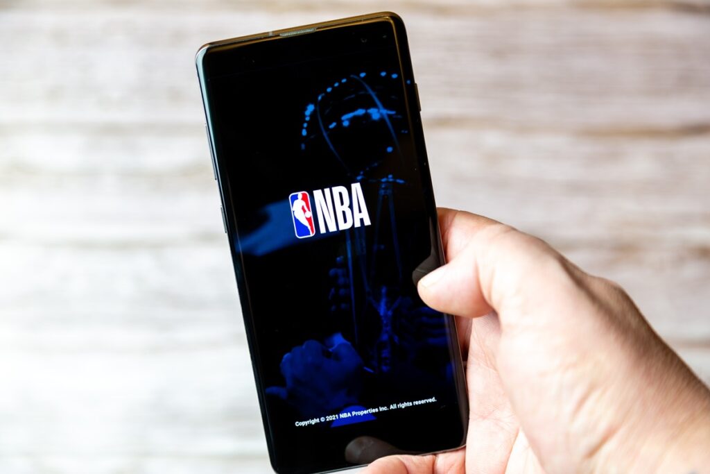 cell phone being held in a hand with the NBA app open on screen