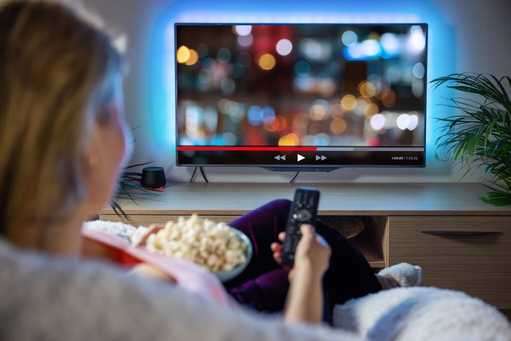 Mulher assistindo filme na televisão com pipoca