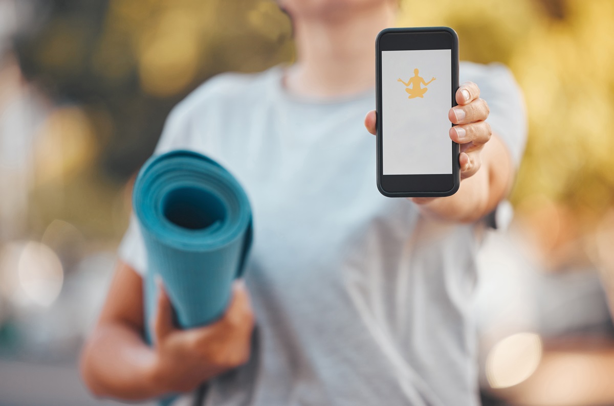 Mulher mostrando celular com app de yoga