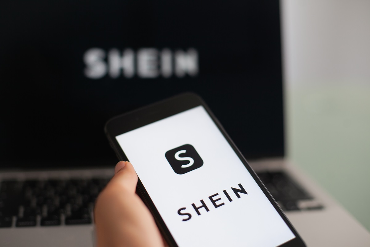 Pessoa segurando celular com app da Shein; Como Ganhar Roupas Grátis da Shein