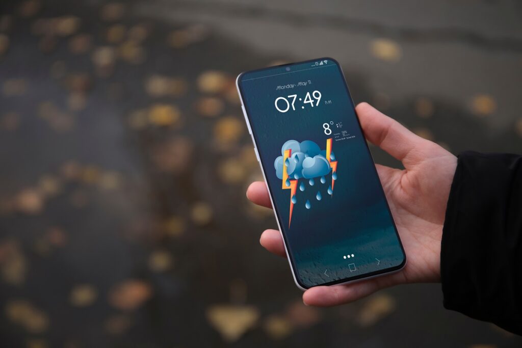 Mão segurando celular com app de previsão do tempo