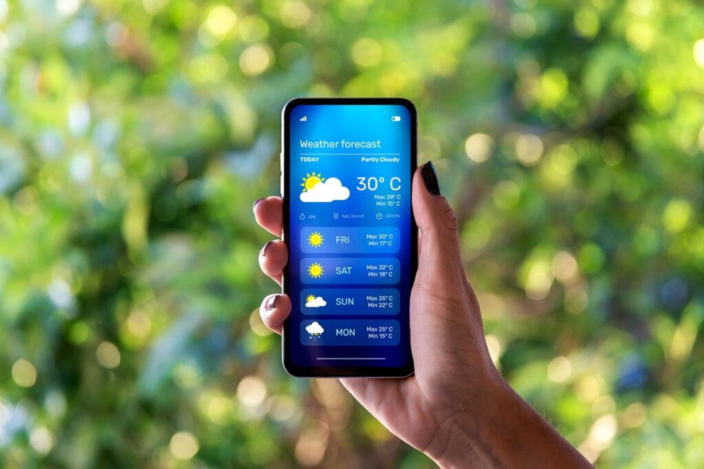 Mão segurando celular com app de previsão do tempo