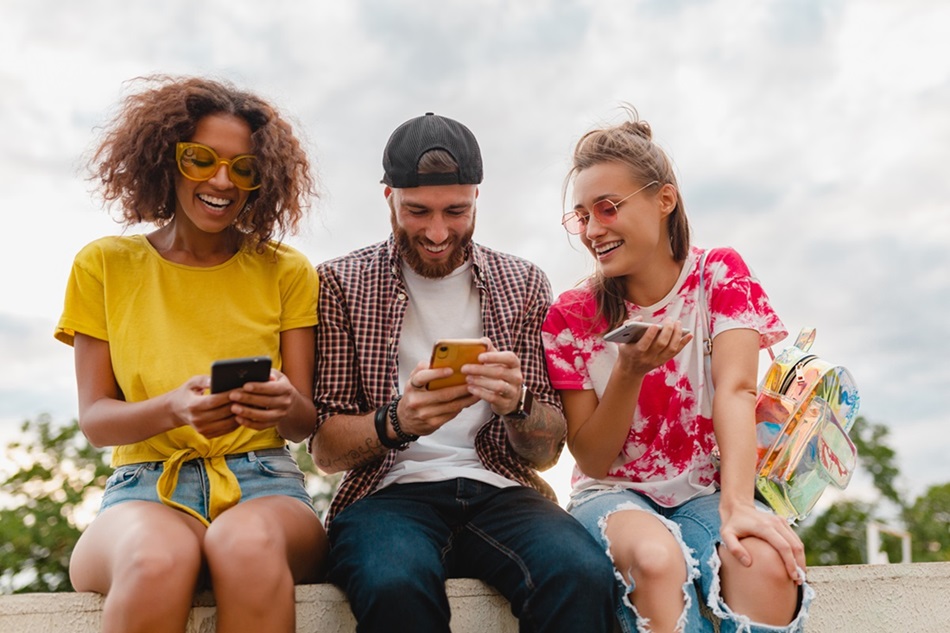 Amigos sorrindo, usando eclular ao ar livre